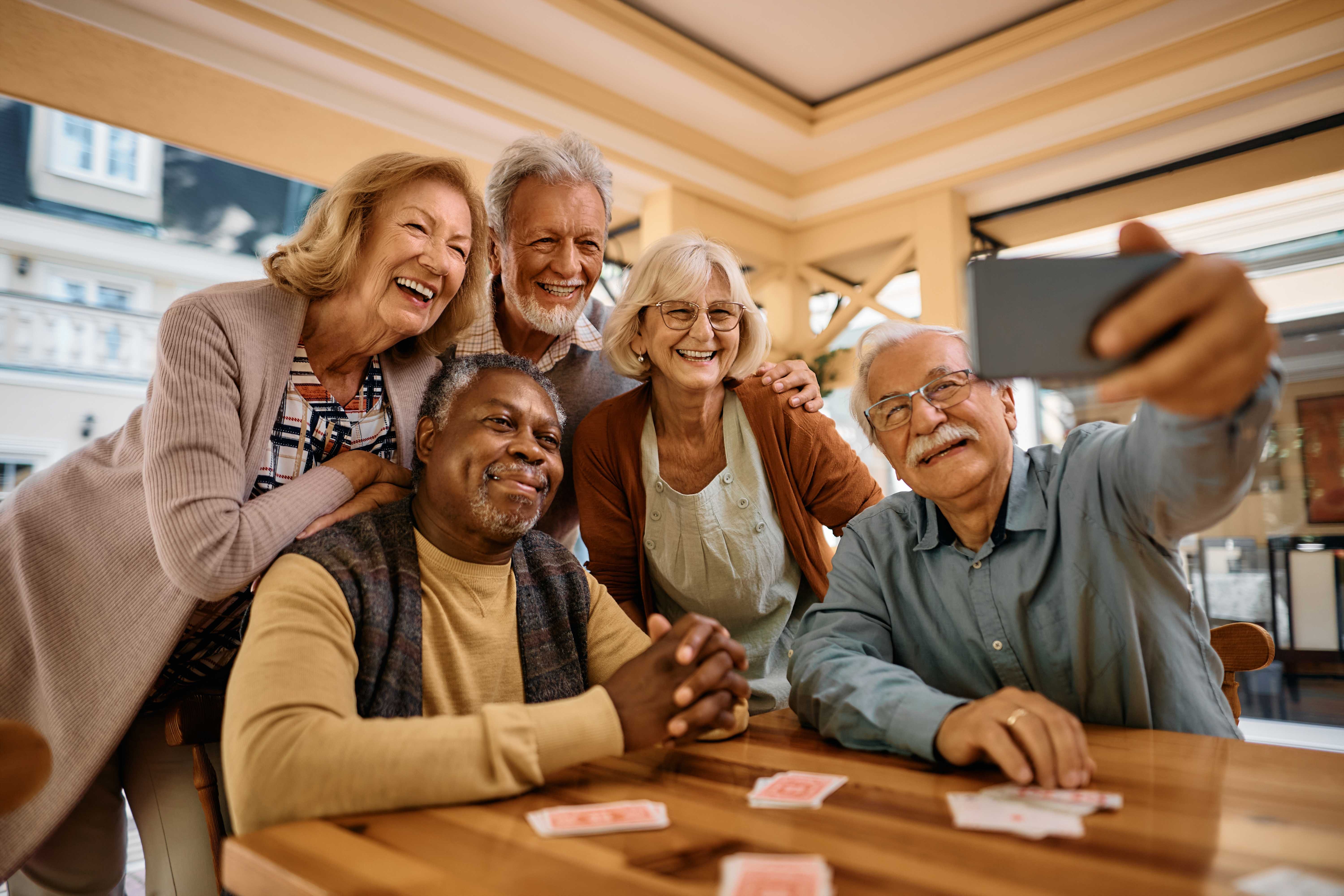 Adult sitting with friends, warm living room gathering, genuine laughter at table
