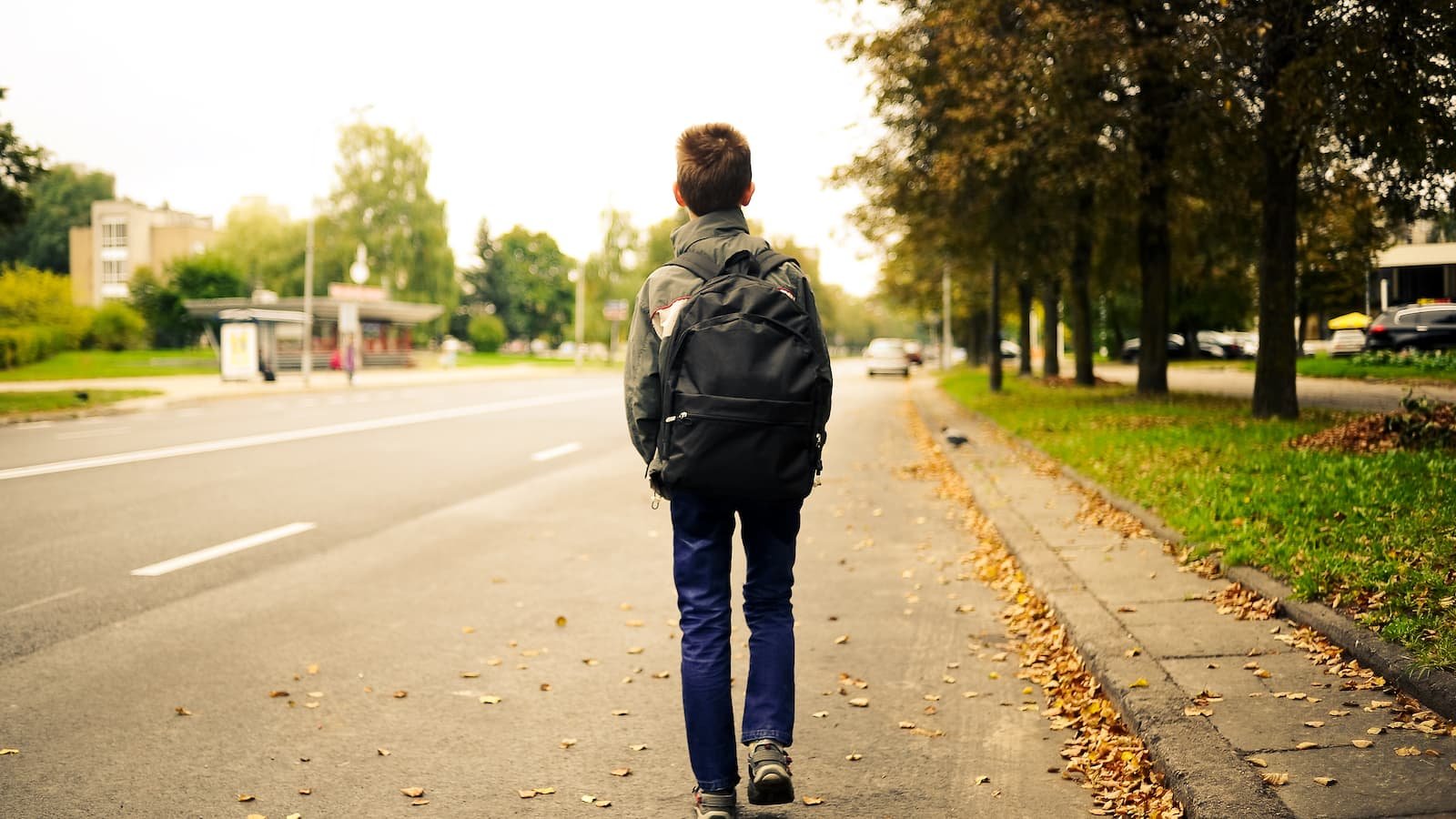 Kid walking home from school, child with backpack alone, suburban sidewalk after school