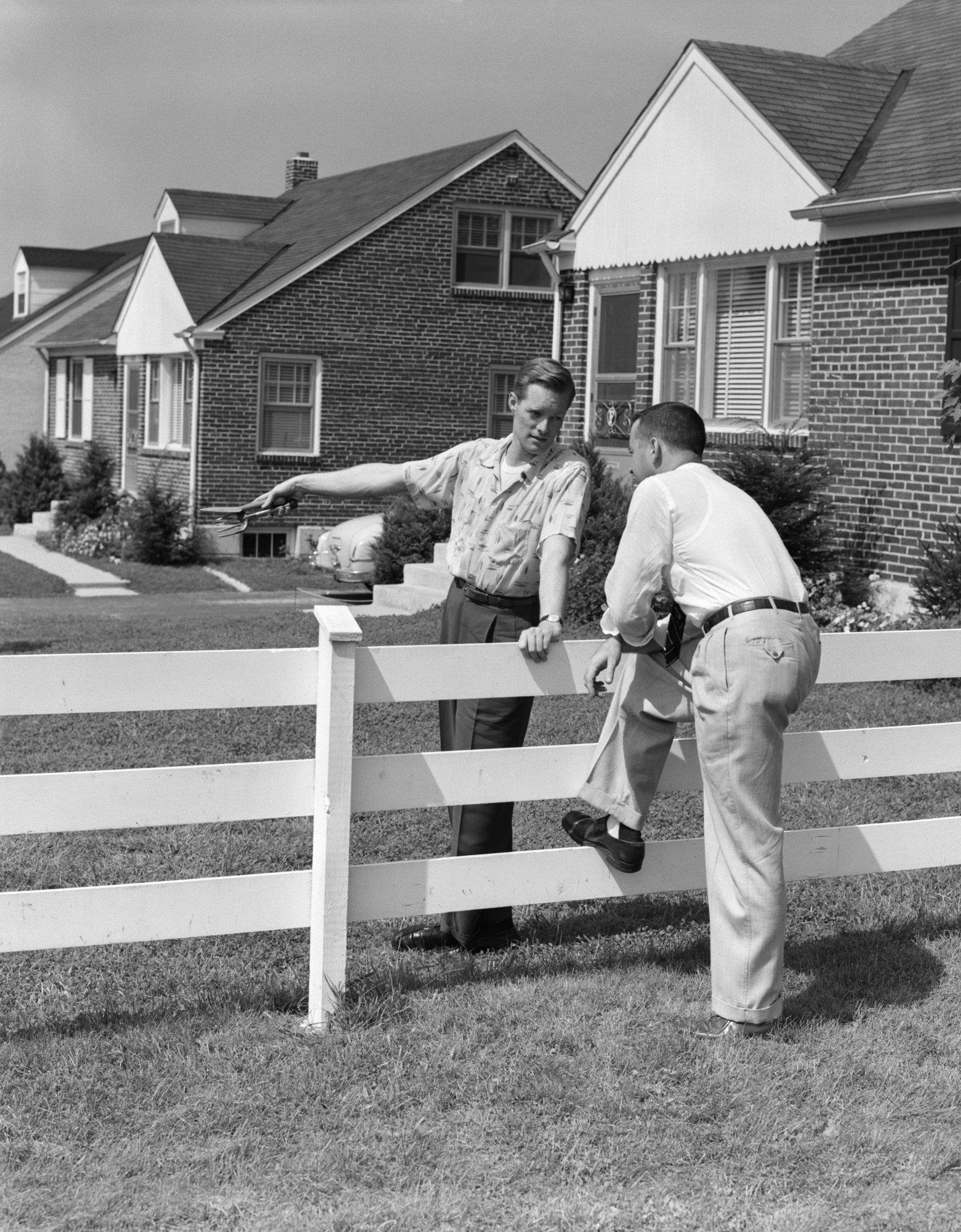 Neighbors chatting over backyard fence