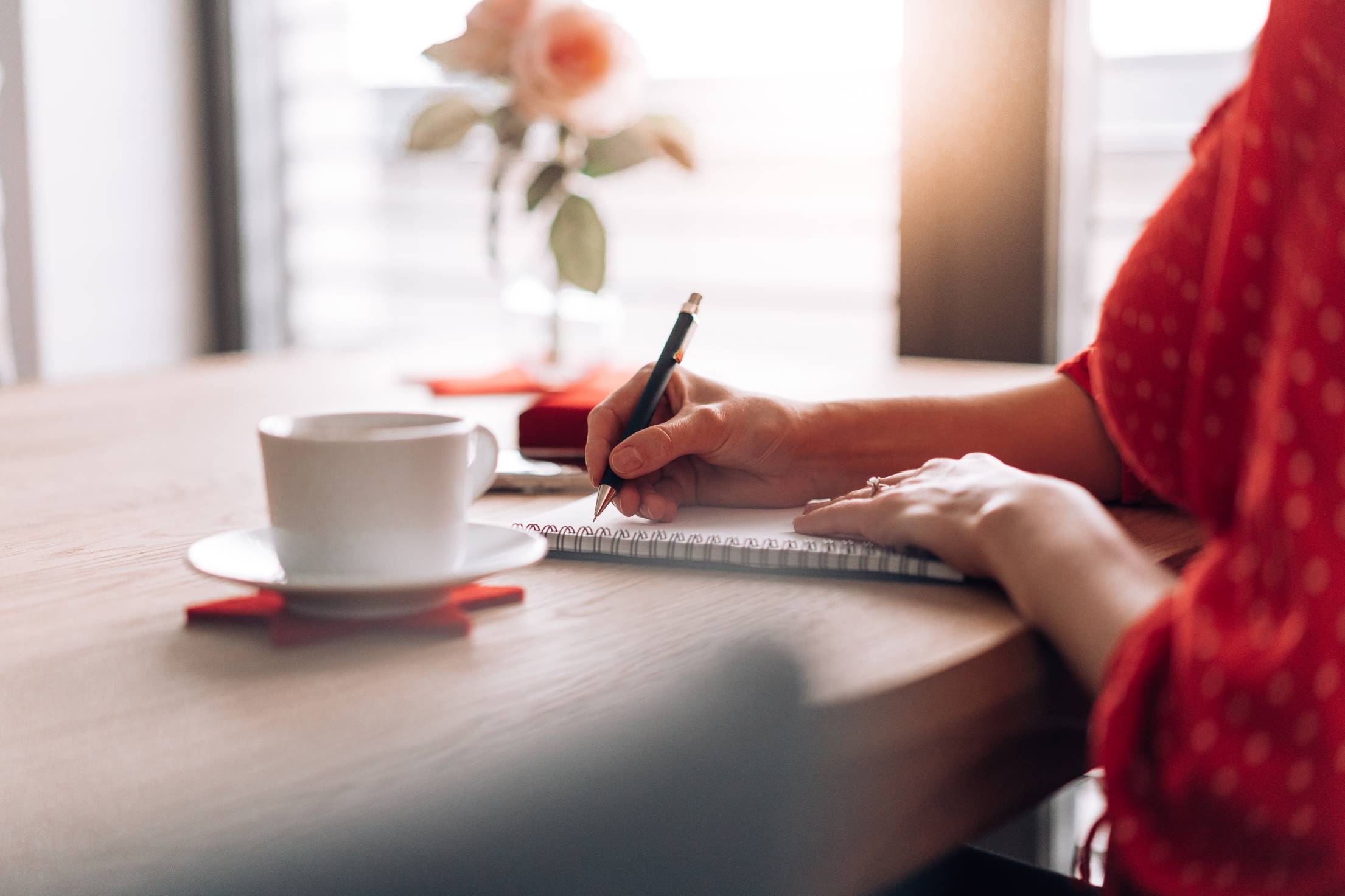 Person journaling at wooden desk