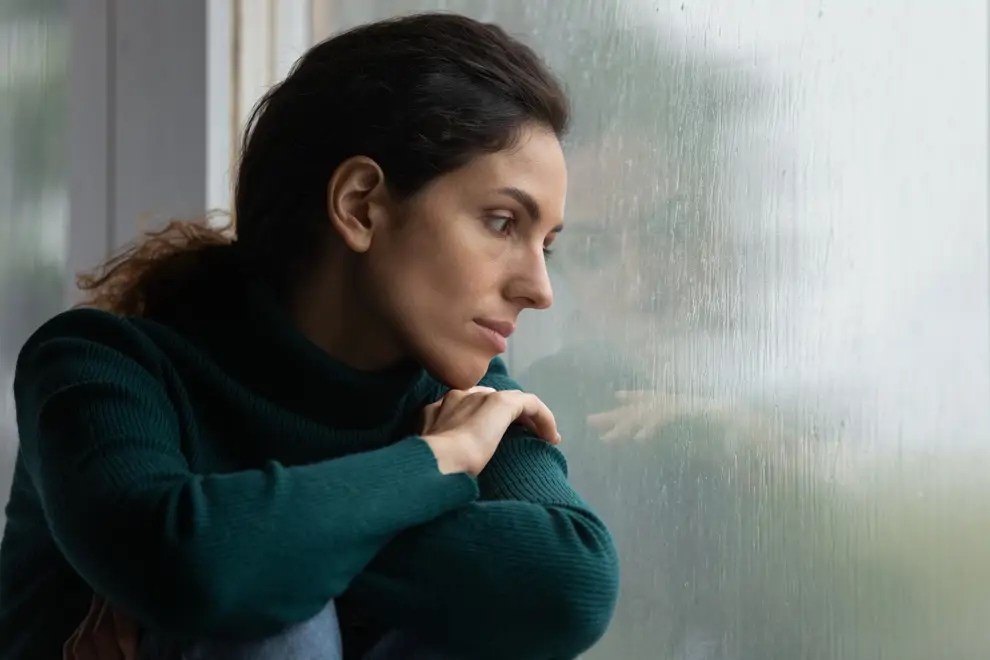 Person looking out window hopeful