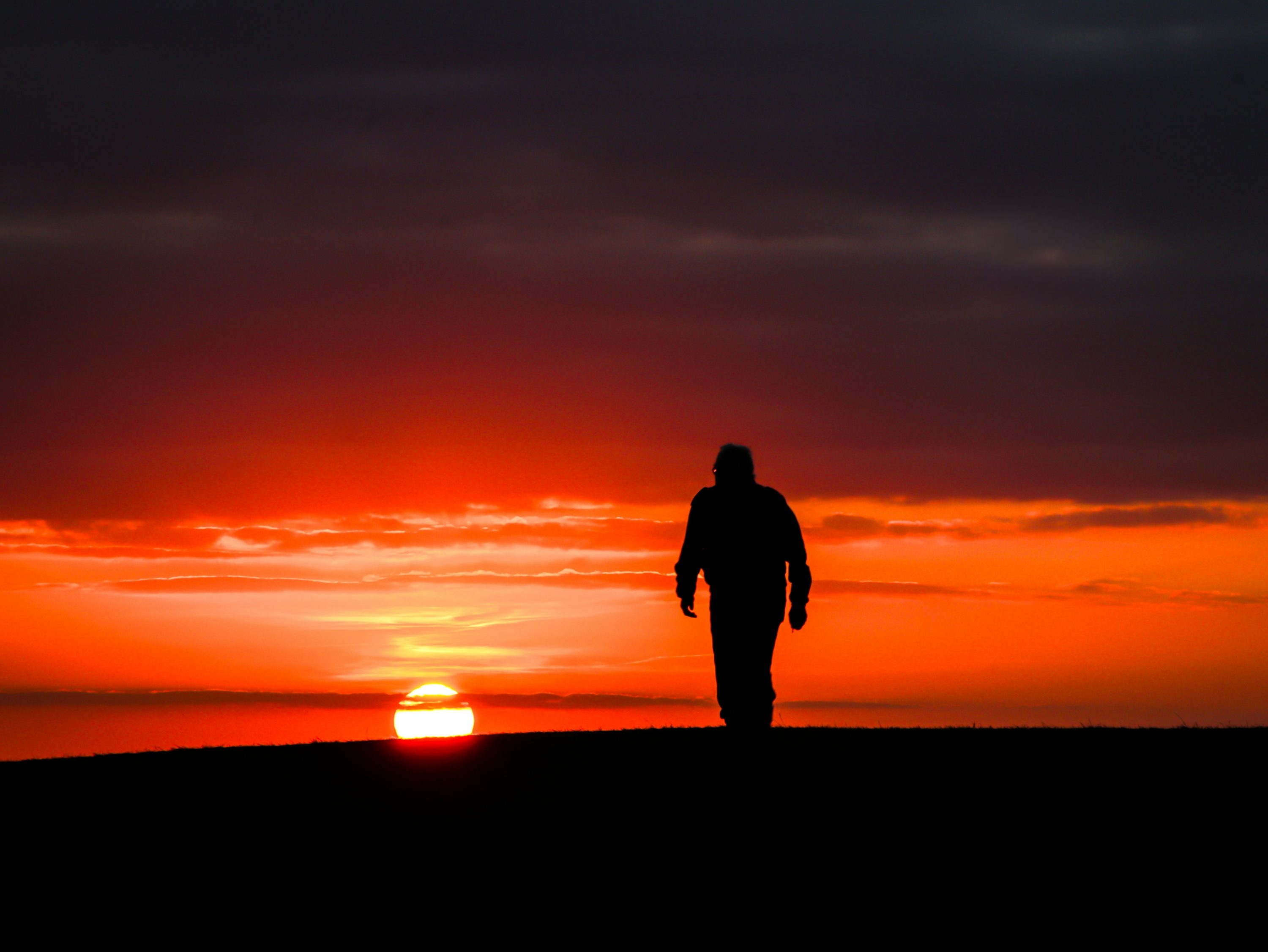 Person walking away at sunset
