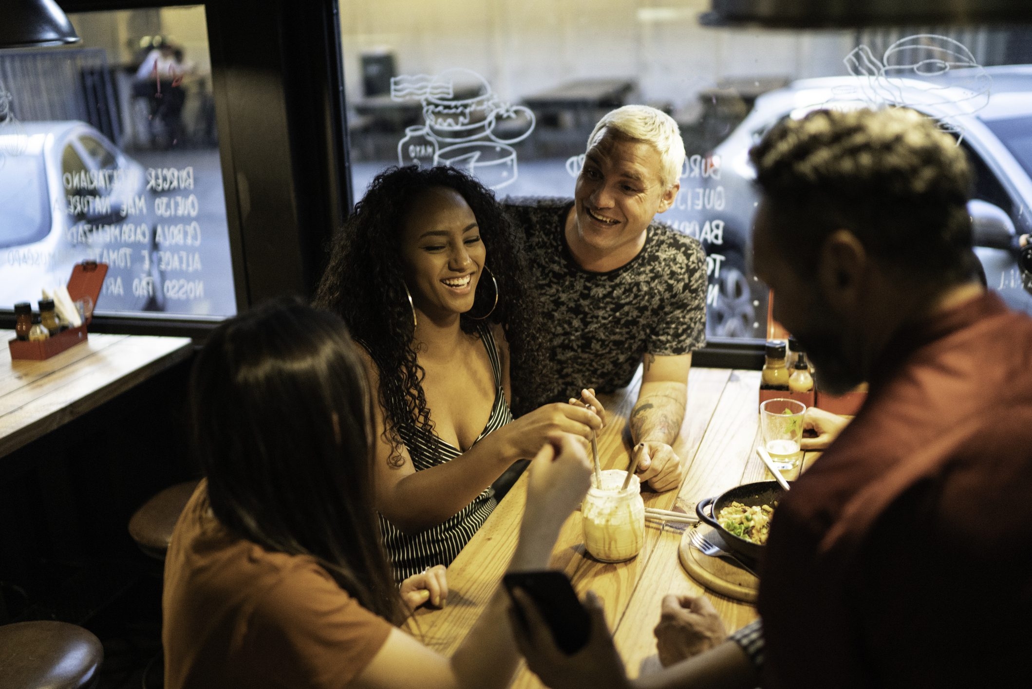 Woman talking and smiling, group of friends at dinner, woman listening attentively